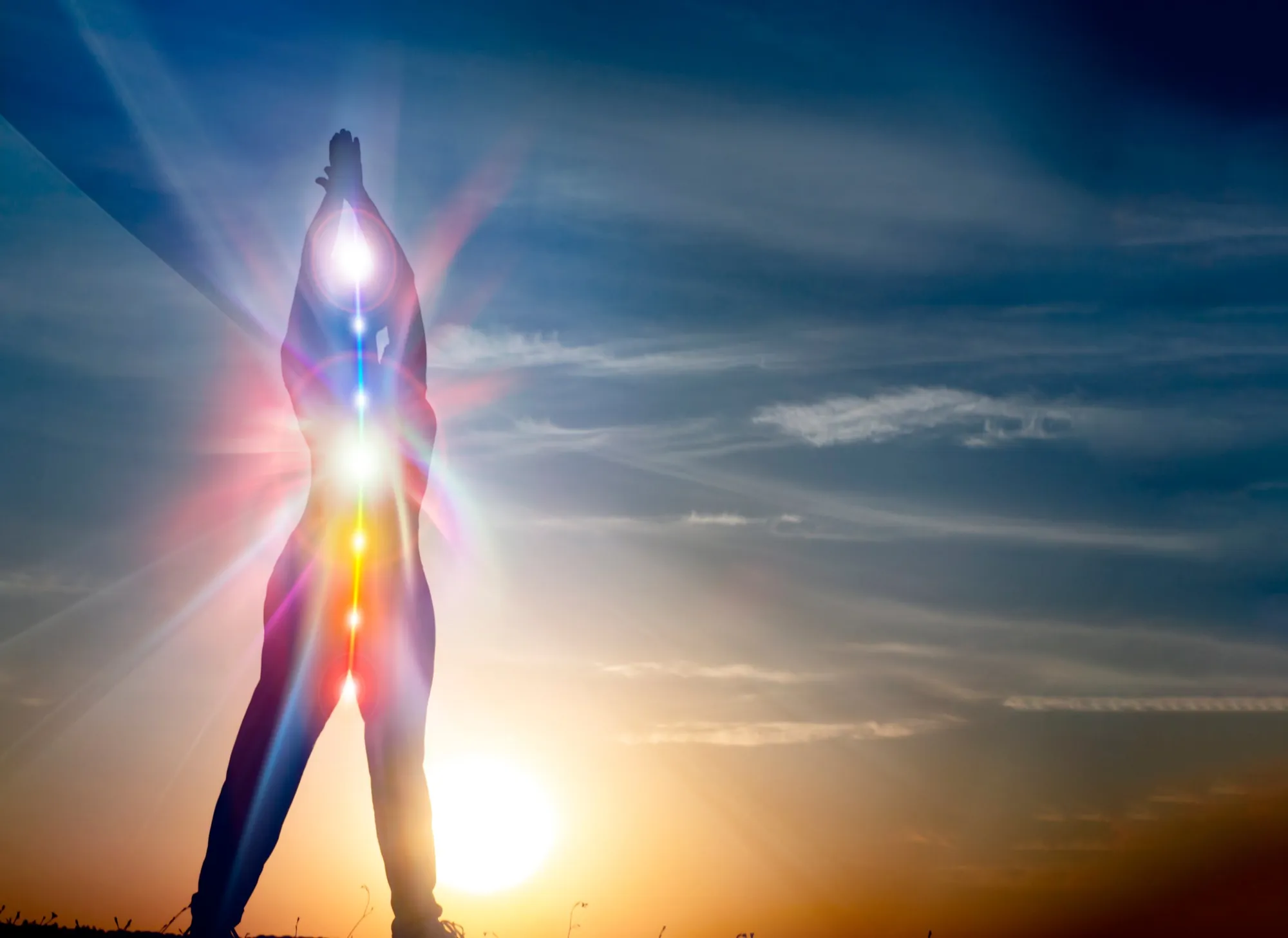 A figure at sunrise, arms raised, light rising through the body